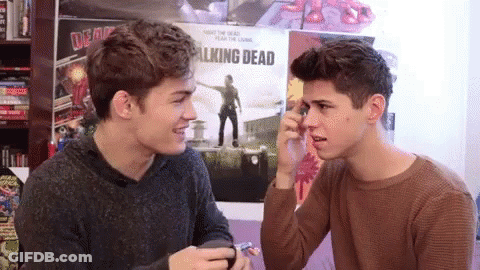 Two Boys Sitting In Front Of Walking Dead Poster GIF