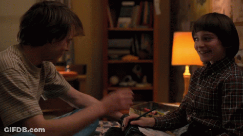Two Boys Sitting On Bed One Covering Face GIF