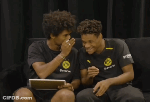 Two Boys Wearing Bvb Shirts Are Sitting On A Couch Laughing GIF