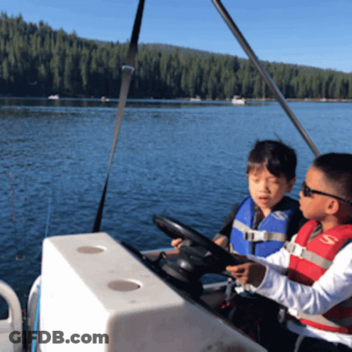 Two Boys Wearing Life Jackets Are Sitting On A Boat GIF