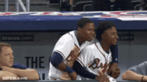 Two Braves Players Are Hugging Each Other In A Dugout GIF