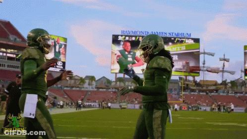 Two Bullpen Football Players Shake Hands In Front Of Raymond James Stadium Billboard GIF