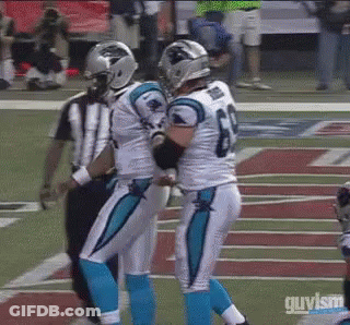 Two Carolina Panthers Football Players Are Hugging Each Other On The Field . GIF