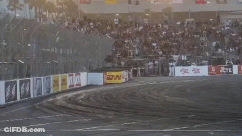 Two Cars Are Drifting On A Track With A Crowd In The Background And A Sign That Says Jcte GIF
