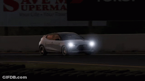 Two Cars Are Driving Down A Road In Front Of A Sign That Says Supermart GIF