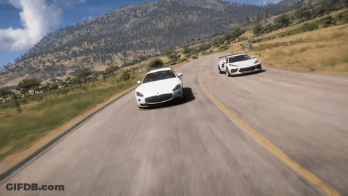 Two Cars Driving Down Road With Mountains GIF
