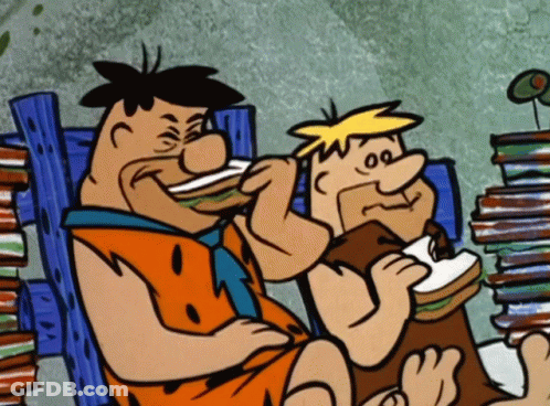 Two Cartoon Characters Eating Sandwiches Next To A Pile Of Books GIF