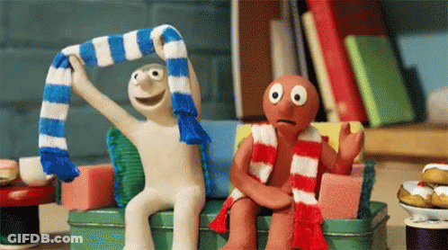 Two Cartoon Characters Sitting On Couch One Wearing Scarf GIF