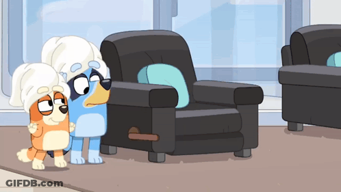 Two Cartoon Dogs Wearing Towels On Their Heads Standing Next To A Chair GIF