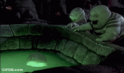 Two Cartoons Look At Glowing Ball In Green Liquid GIF