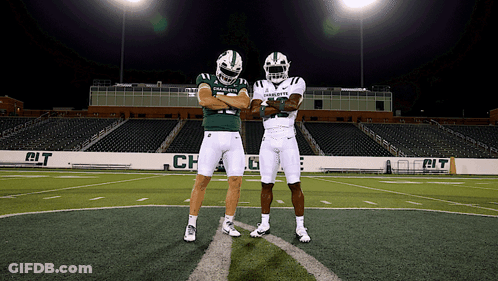 Two Charlotte Football Players Standing On A Field GIF