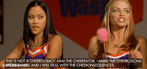 Two Cheerleaders Are Standing In Front Of A Sign That Says Waste GIF