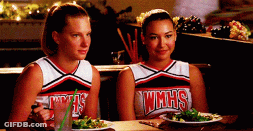 Two Cheerleaders From WMHS Sitting At Table GIF