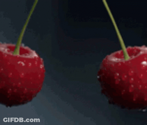 Two Cherries Are Being Sprayed With Water On A Black Background GIF