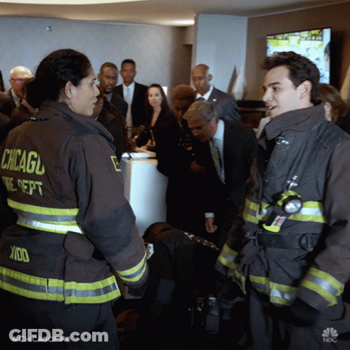 Two Chicago Firefighters Talking In Front Of Crowd GIF