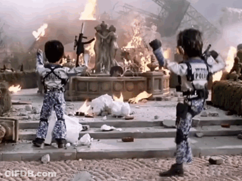 Two Children In Police Uniforms Before Burning Building GIF