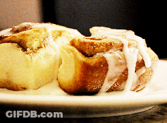 Two Cinnamon Rolls On A White Plate With Icing On Them GIF