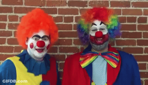 Two Clowns Are Standing Next To Each Other In Front Of A Brick Wall And Smiling . GIF