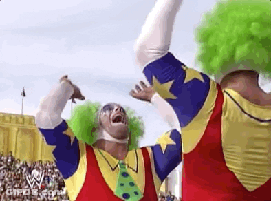Two Clowns Are Standing Next To Each Other In Front Of A Crowd In A Stadium . GIF