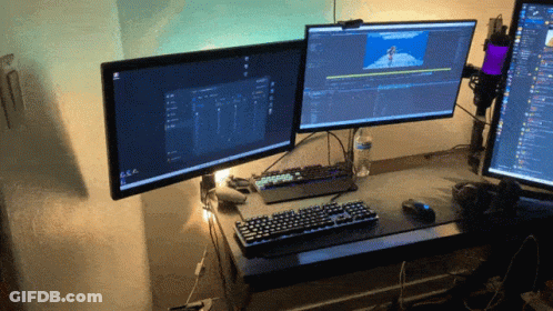 Two Computer Monitors Are Sitting On A Desk With A Keyboard GIF