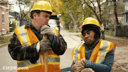 Two Construction Workers In Hard Hats And Vests GIF