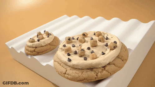 Two Cookies With Frosting And Chocolate Chips On Them GIF