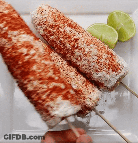 Two Corn On The Cob On Skewers On A White Plate With Limes . GIF