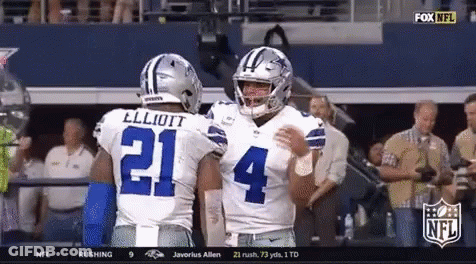 Two Cowboys Football Players Are Hugging Each Other In The Stands GIF