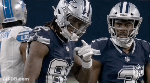 Two Cowboys Football Players Are Standing Next To Each Other On The Field And Pointing At Each Other . GIF