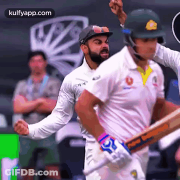 Two Cricket Players Are Playing A Game Of Cricket And One Of Them Is Wearing A Helmet With The Word Cricket On It GIF