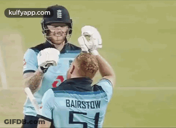 Two Cricket Players Are Shaking Hands On The Field . GIF