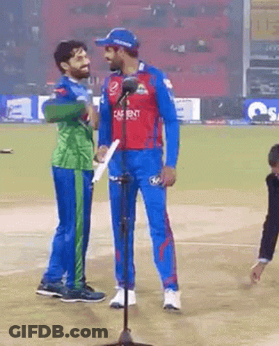 Two Cricket Players Are Standing Next To Each Other On A Field . GIF