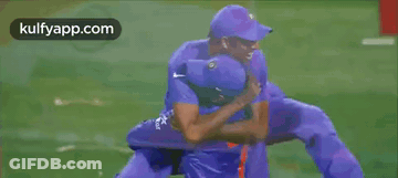 Two Cricket Players Hugging Each Other On A Field GIF