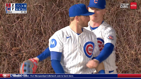 Two Cubs Baseball Players Are Hugging Each Other In Front Of A Scoreboard That Says Stream Cubs GIF