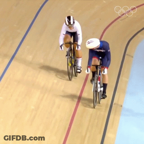Two Cyclists Are Racing On A Track With The Olympic Rings On The Bottom GIF
