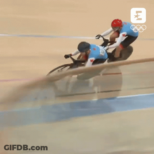 Two Cyclists Are Racing On A Track With The Olympics Logo GIF