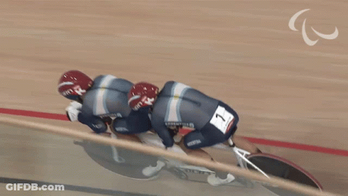Two Cyclists Wearing Giro Helmets Are Riding A Tandem Bike GIF