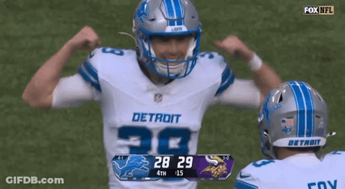 Two Detroit Football Players Flexing Muscles In Front Of Scoreboard GIF