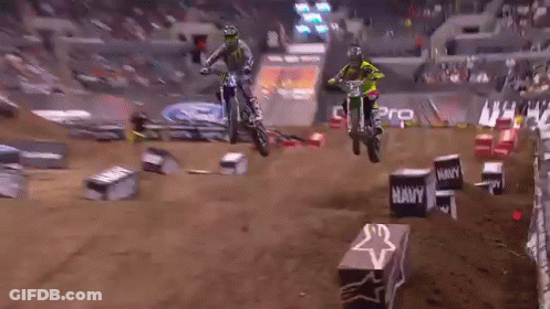 Two Dirt Bike Riders Are Jumping Over Boxes That Say Navy GIF