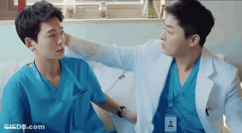 Two Doctors In Scrubs Are Talking To Each Other In A Hospital Room GIF