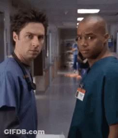 Two Doctors Standing Next To Each Other In A Hospital Hallway . GIF