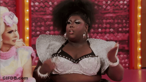 Two Drag Queens Are Sitting Next To Each Other And One Of Them Is Wearing A Bra With Pearls On It GIF
