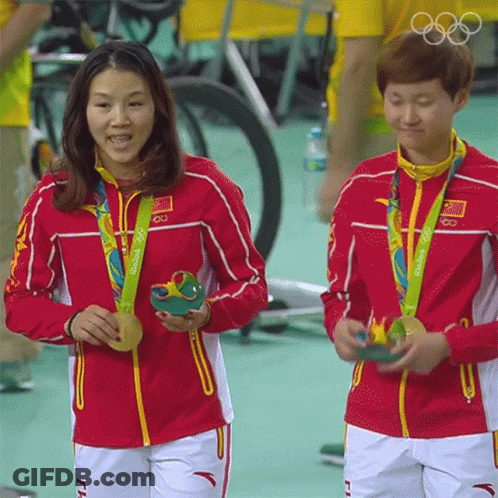 Two Female Athletes From China Are Holding Their Medals GIF