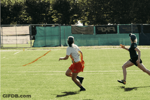 Two Female Athletes Running On Field With BKF Banner GIF