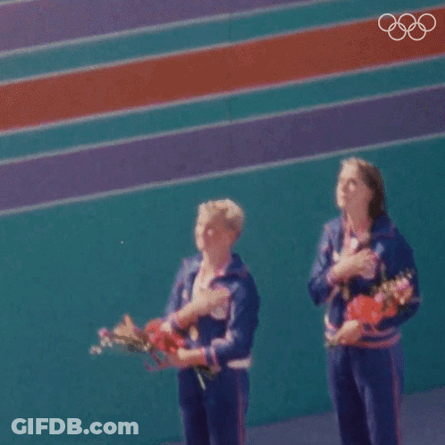 Two Female Athletes Standing With Hands On Chest GIF