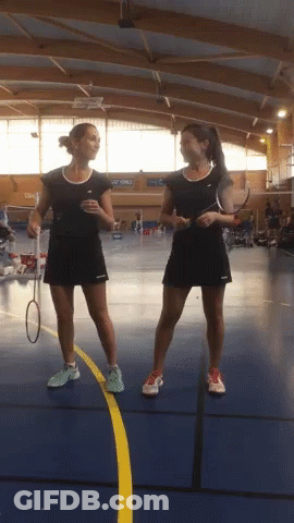Two Female Badminton Players Standing Next To Each Other On A Blue Court GIF