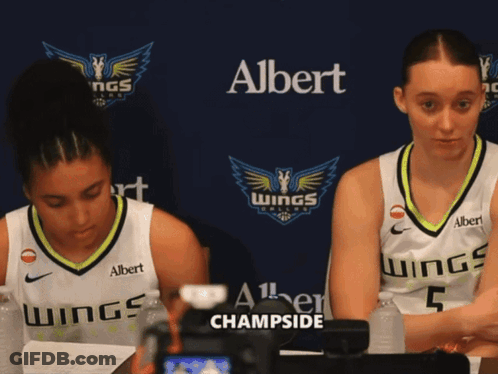 Two Female Basketball Players Are Sitting In Front Of A Banner That Says Albert Champside GIF