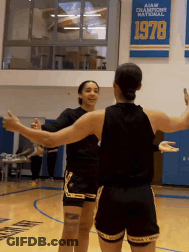 Two Female Basketball Players Hugging In Front Of AIAW Champions National 1978 Banner GIF