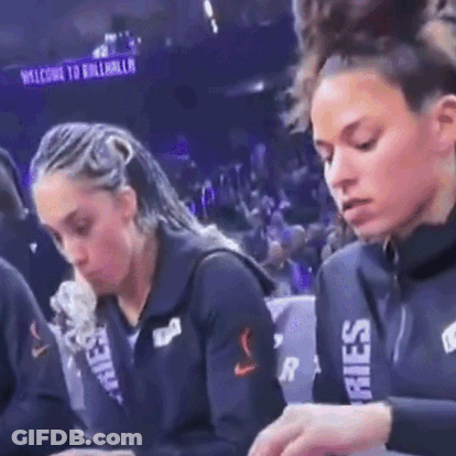 Two Female Basketball Players Sitting At Table In Front Of Crowd GIF