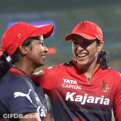 Two Female Cricket Players Are Standing Next To Each Other On The Field And Smiling . GIF